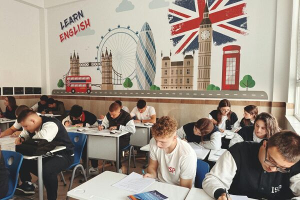 Students studying English in a classroom with British themed decor and mural.
